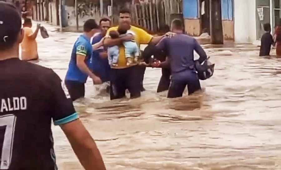 VÍDEO: moradores fazem corrente humana para ajudar pai com gêmeos de 2 meses a atravessar rua alagada no Acre